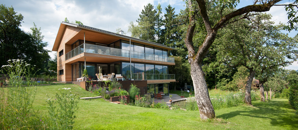 Freistehendes Haus mit Glasfront und Holz mit Blick in großen Garten