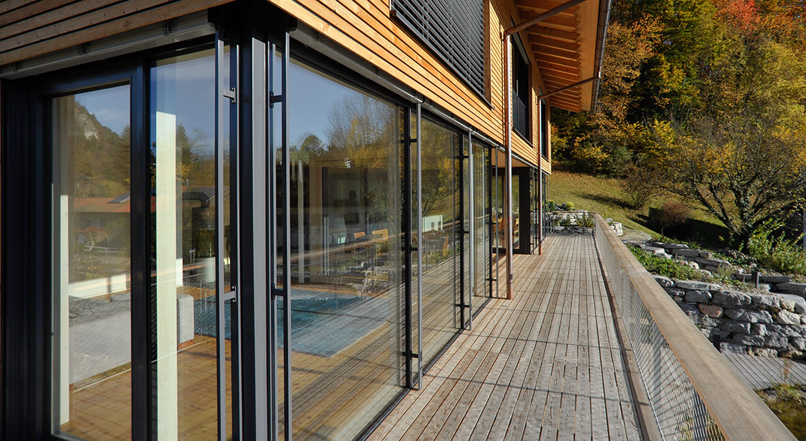Passivhaus mit Holzbalkon mit Blick auf komplette Glasfront